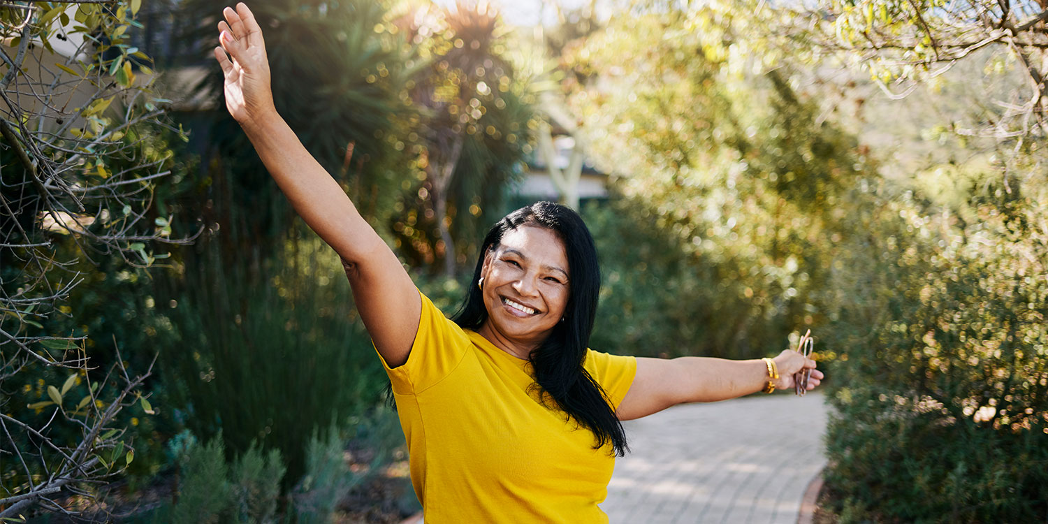 Woman outdoors on a sunlit path with arms outstretched, tracking her longevity dashboard for shifts in her longevity baseline and baseline trends over time.