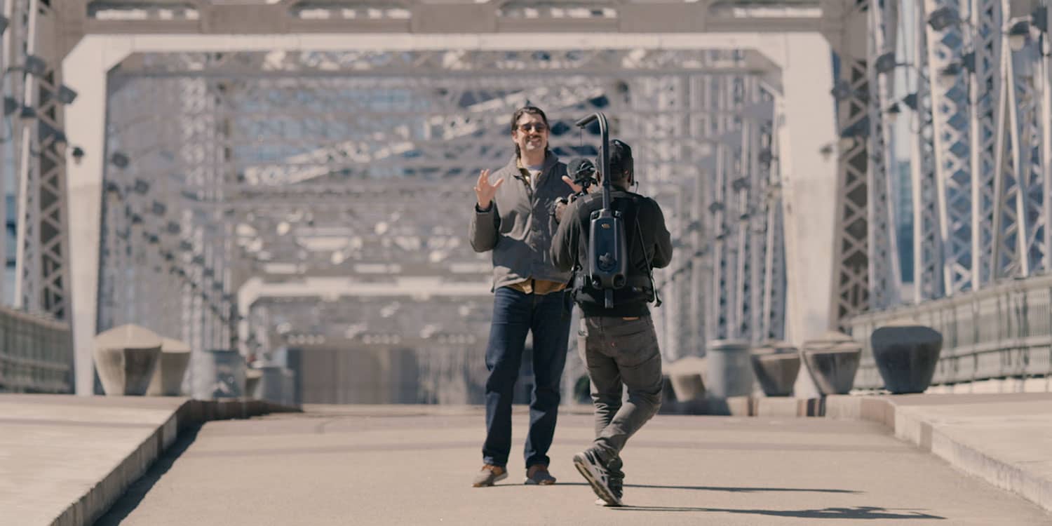 A Nashville host films on a pedestrian bridge for a story about movement and chiropractic care.
