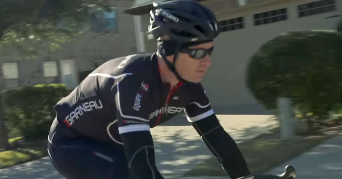 Richard, a triathlete living with fibromyalgia pain, rides his road bike through a suburban neighborhood in full cycling gear.